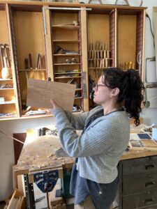 Woman examines her progress on a woodworking project.