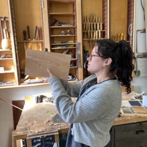 Woman examines her progress on a woodworking project.